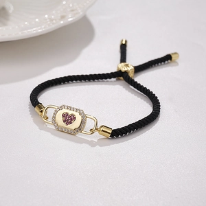 Macro detail of adjustable black woven bracelet with zircon-encrusted heart lock charm