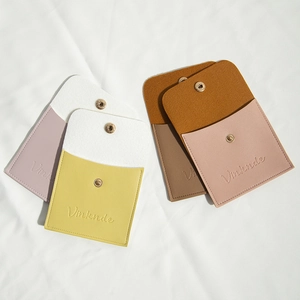 Detail of multi-color PU leather jewelry pouches with snap buttons on white fabric