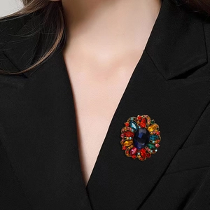 Retro rhinestone floral brooch with deep blue center stone on a black suit lapel