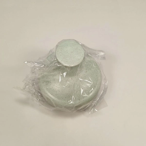 Close-up of a mint green straw material hair scalp massager in clear plastic packaging