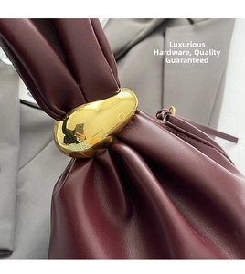Close-up of luxury burgundy leather bag with high-quality gold hardware and elegant texture