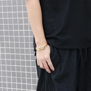 Detail of twisted cable gold bracelet with silver end caps on male model wrist