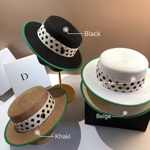 Detail of four straw boater hats with polka dot ribbons and green edges on a display stand