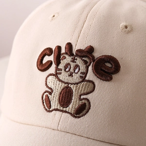 Dettaglio del cappellino in cotone beige con ricamo 3D di una tigre carina e testo