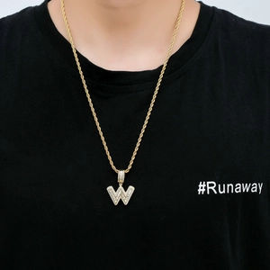Close-up of hip hop iced out letter W pendant with gold twist chain on a model