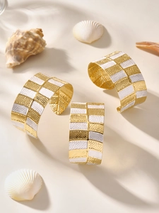Dettaglio del bracciale rigido a scacchi oro e bianco con motivo a onde testurizzato