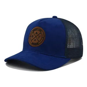 Close-up of royal blue suede trucker hat with round leather patch and breathable black mesh
