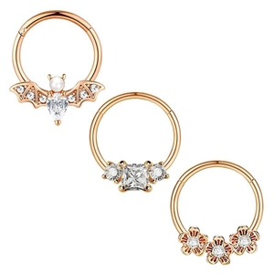 Detailed macro view of 3-piece rose gold nose rings with bat, floral, and gem designs