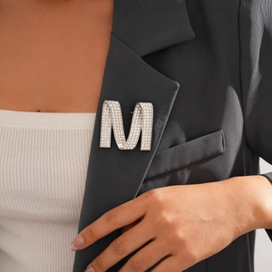 Elegant silver letter M brooch with rhinestones on a charcoal grey suit lapel