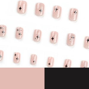 Sparkly nude pink press-on nails with black star patterns and tiny rhinestones