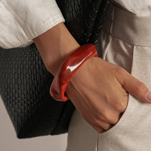 Vue macro d'un large bracelet en acrylique rouge aux motifs tourbillonnants ambrés