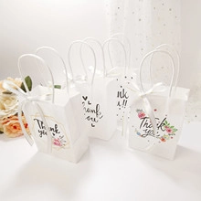 Macro shot of elegant white paper gift bags with handles, ribbon bows and floral patterns