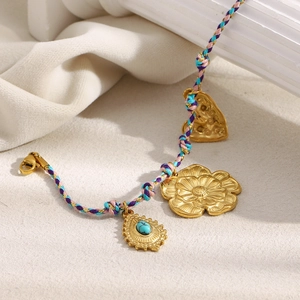 Dettaglio di ciondoli a fiore e turchese placcati oro 18K su un bracciale intrecciato rosa e blu