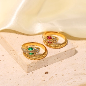 Detail of 18K gold snake rings with green and red zircon eyes on textured stone