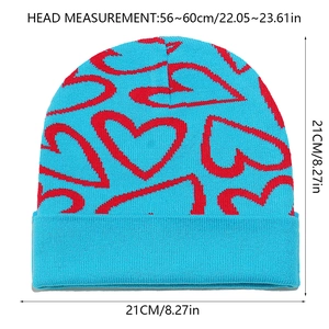 Detail view of blue knit beanie showing red heart patterns and size dimensions 21x21cm