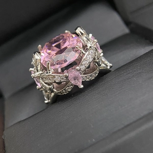 Macro shot of large pink oval gemstone ring with silver floral setting in jewelry box