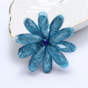 Macro shot of blue resin flower brooch with fiber texture and a sparkling rhinestone