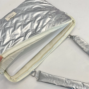 Detailed view of silver quilted laptop bag with bow pattern and white zipper closure