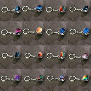 Detail view of 16 assorted galaxy glass dome keychains featuring nebula patterns
