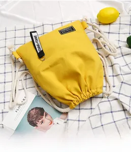 Detailed view of yellow canvas drawstring bag with woven labels on checkered background