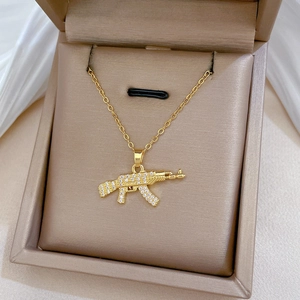 Close-up of golden AK-47 rifle pendant with sparkling crystals in a beige jewelry box