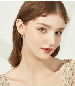 Detailed view of elegant gold hook earrings with blue moissanite on a model