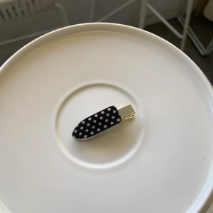 Macro view of polka dot iron-shaped hair clip on a white ceramic plate accessory