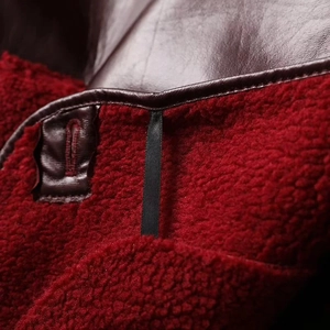 Detail of burgundy leather jacket featuring plush red faux shearling lining and hanging loop