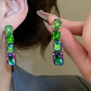 Detailed close-up of rectangular crystal earrings featuring green and blue gradient stones