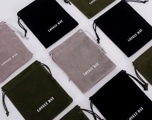 Close-up of velvet drawstring pouches in black, grey, and green with Lovely Day print