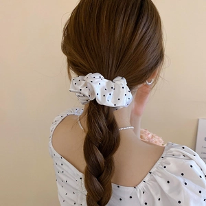 Detailed view of white polka dot scrunchie styled on a brunette ponytail
