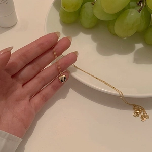 Close-up of a stylish gold heart pendant necklace styled with elegant white plate and grapes