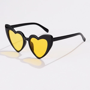 Detail of heart-shaped sunglasses featuring black frames and vibrant yellow lenses