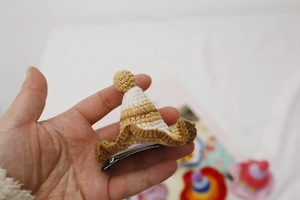 Close-up of a handmade crochet mini hat hair clip in brown and beige with pom-pom