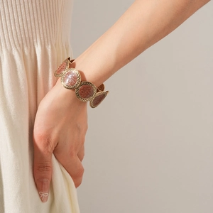 Detail of vintage gold bangle with pink leopard print round resin charms on model
