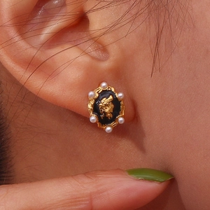 Macro shot of vintage 18K gold-plated earring featuring cameo portrait and white pearls