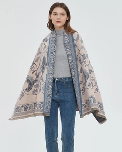 Detail view of beige woven shawl featuring blue paisley floral patterns and fringed edges
