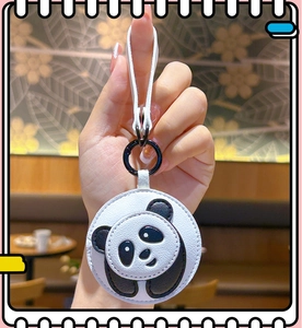 Close-up of a panda leather keychain featuring a round charm with a black metal hook