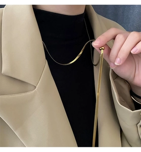 Close-up of adjustable gold snake chain necklace worn on a black turtleneck and blazer
