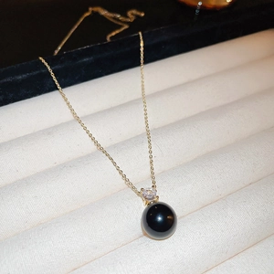 Macro shot of an elegant black pearl pendant with a sparkling diamond on a gold chain