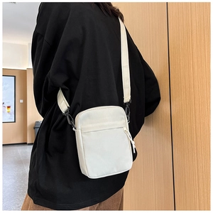 Rear view of a minimalist white canvas crossbody bag with adjustable nylon shoulder strap