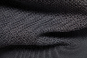 Macro shot of dark grey knit polo shirt fabric showing fine pineapple texture and weave