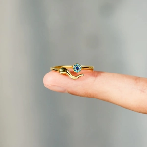 Close-up of golden S925 sterling silver evil eye ring with blue cluster and curved tail