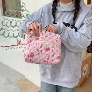 Détail d'une trousse en coton matelassé rose avec motifs lapin et fraises à la main