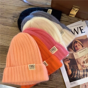 Close-up of colorful knit beanies with 1982 California label on a wooden table