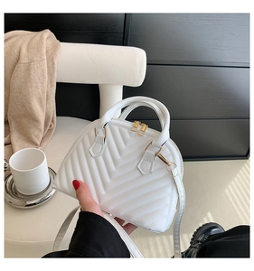Close-up of white shell-shaped bag featuring V-shaped quilting and gold metal hardware