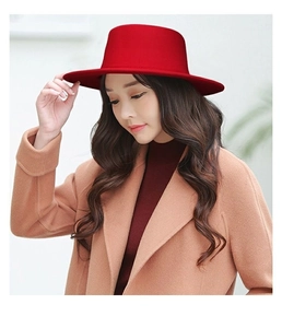 Dettaglio di un elegante cappello di lana rosso a tesa larga e corona piatta su modella