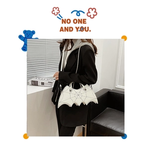 Detail view of white bat shaped gothic bag with black spider web stitching and metal rivets