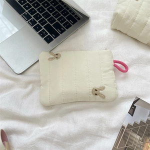 Detail of cream quilted makeup bag with cute rabbit embroidery and pink zip puller