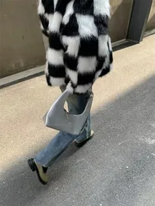 Silver metallic crescent handbag styled with a trendy faux fur coat and denim jeans